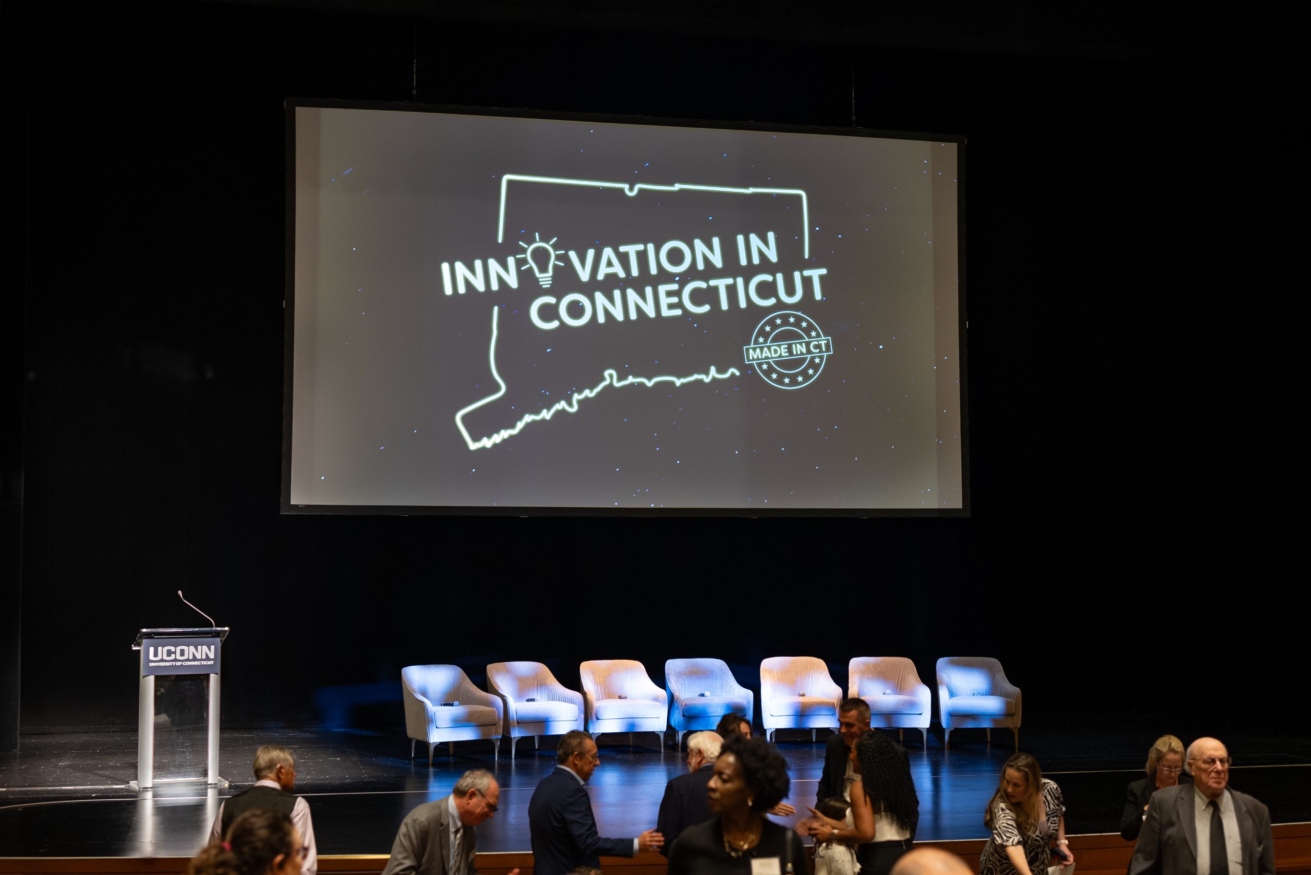 "Innovation Connecticut" on a screen with a row of chairs on the stage