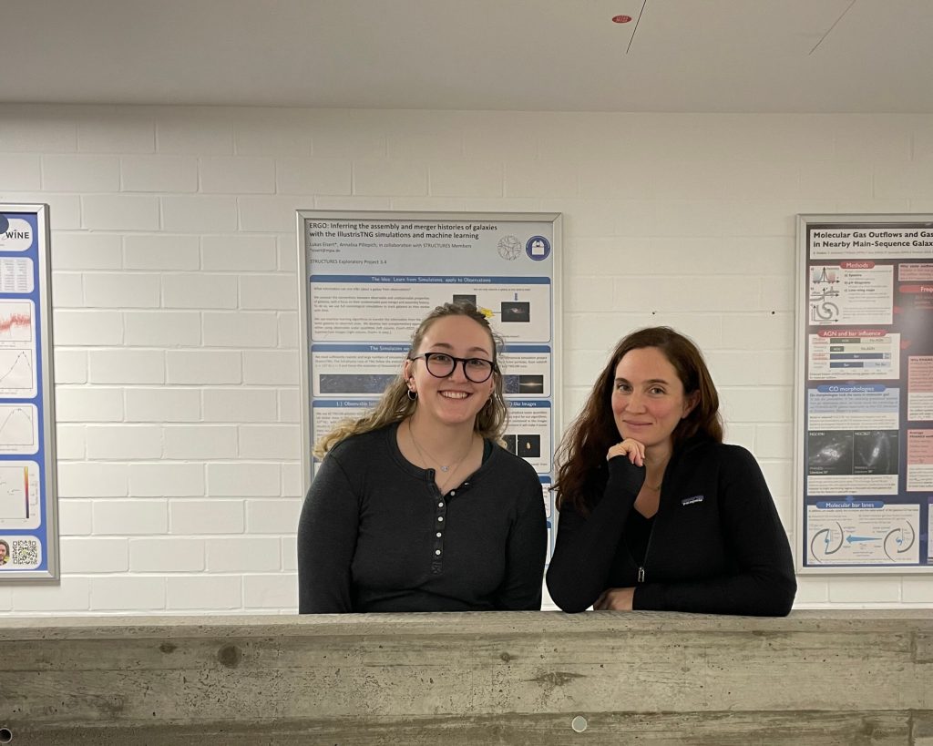 Cara Battersby and Rachel Lee pose in front of scientific posters on the wall.