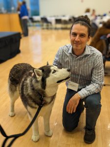 A man kneels next to a fluffy Husky dog