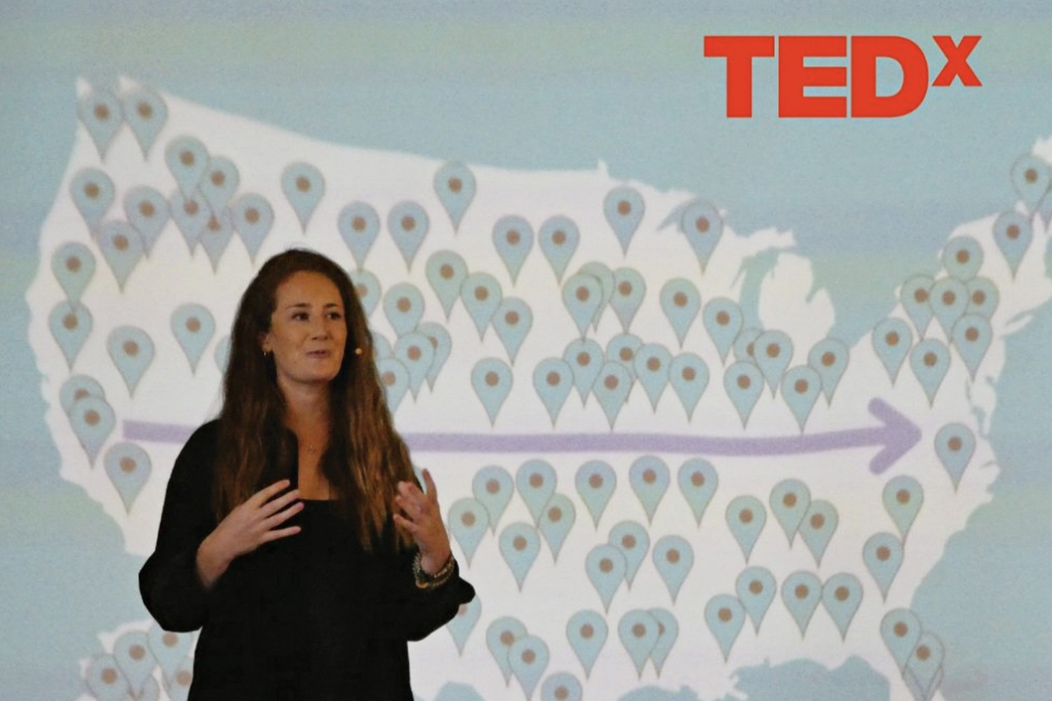 Michelle Wax stands in front of large screen while giving TedX talk