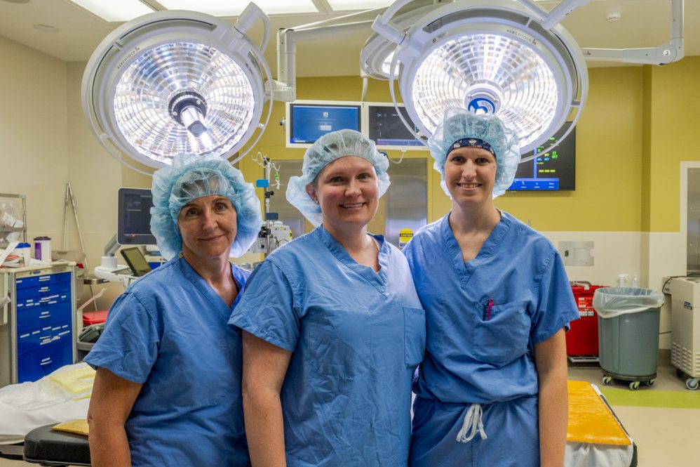 portrait of three physician assistants in scrubs in operating room