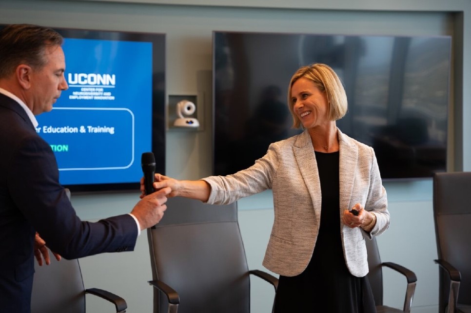 Judy Reilly handing a microphone to someone at a conference.