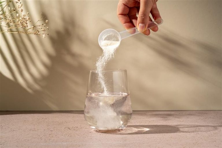 A scoop of nutritional powder is poured into a glass of water