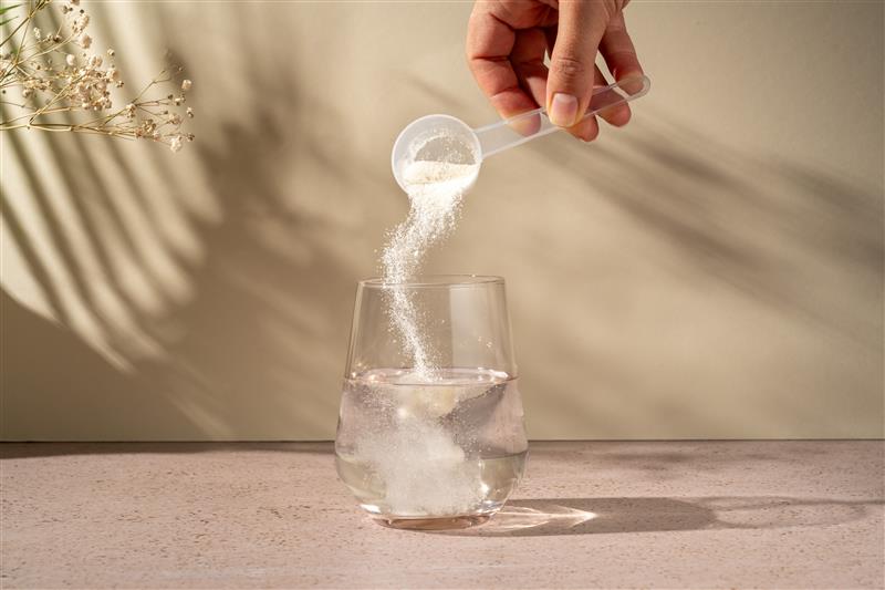 A scoop of nutritional powder is poured into a glass of water