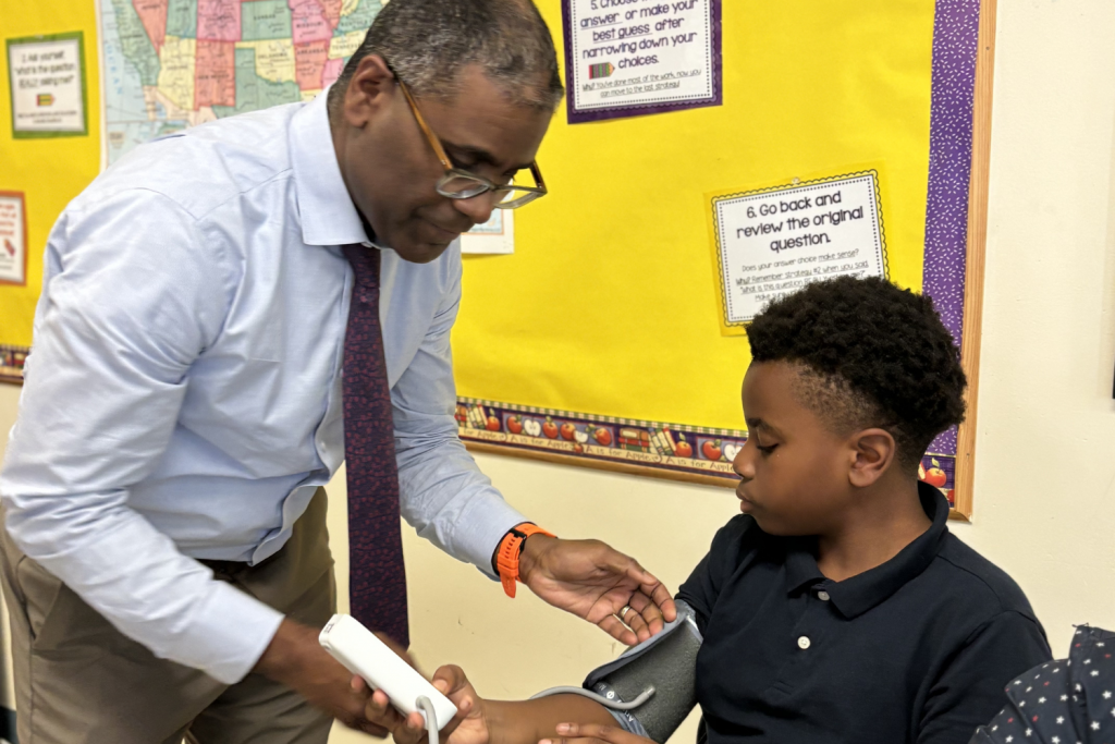 Vascular Surgeon Dr. Kwame Amankwah of UConn Health at Hartford's Covenant Prep teaching the importance of hands-on health skills to six-grade students like blood pressure.