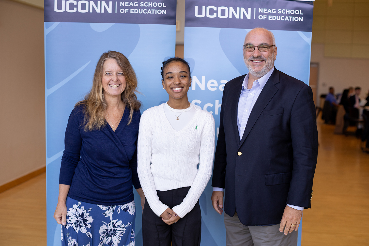 Two adult professionals gather (left and right) gather with female student.