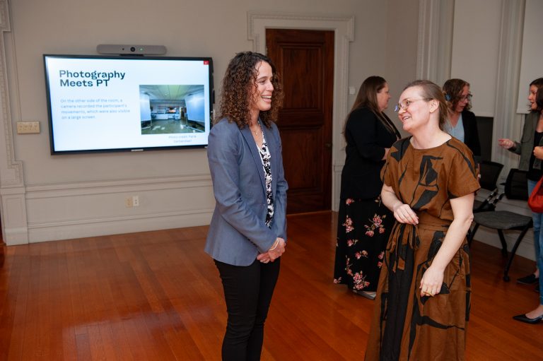 Cristina Colón-Semenza, assistant professor in UConn’s Department of Kinesiology, talks with Clare Benson, a former UConn assistant professor of photography, at the Nov. 7 opening of their exhibition, 