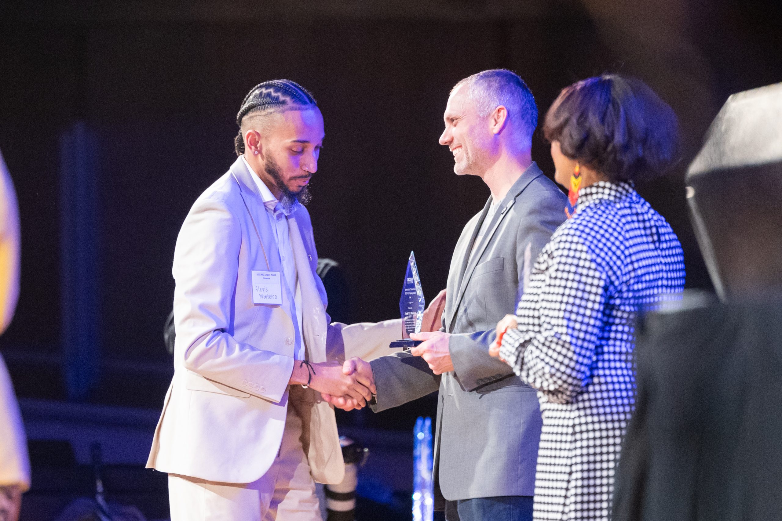 Vice President for Student Life and Enrollment at UConn Nathan Fuerst gives Alexis Monteiro, a residence hall director at UConn, the 2025 MLK Legacy Award for staff during the Dr. Martin Luther King Living Legacy Convocation