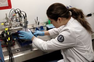 researcher in lab coat using machine in lab