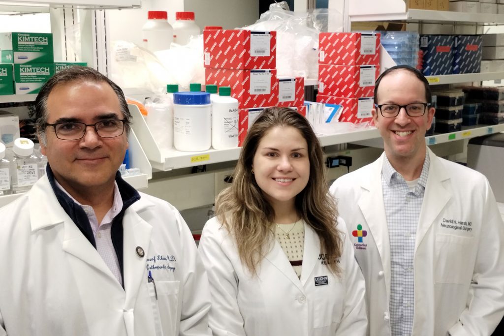 portrait of three researchers in lab coats in front of lab bench