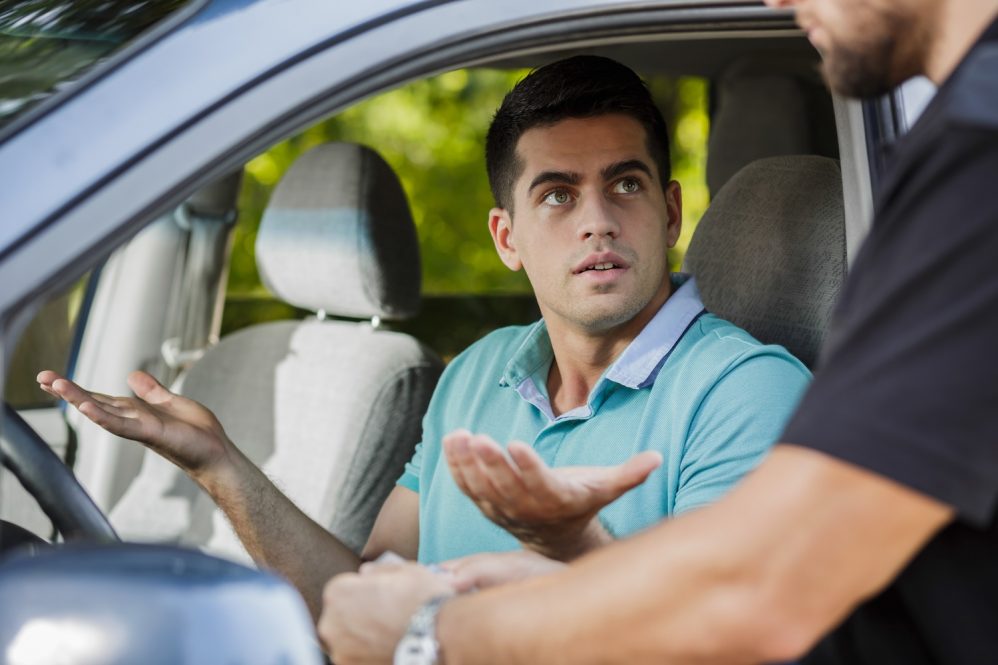 Confused young man in the car stopped by policeman