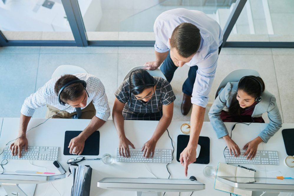 High angle shot of a man assisting his colleagues in a call center