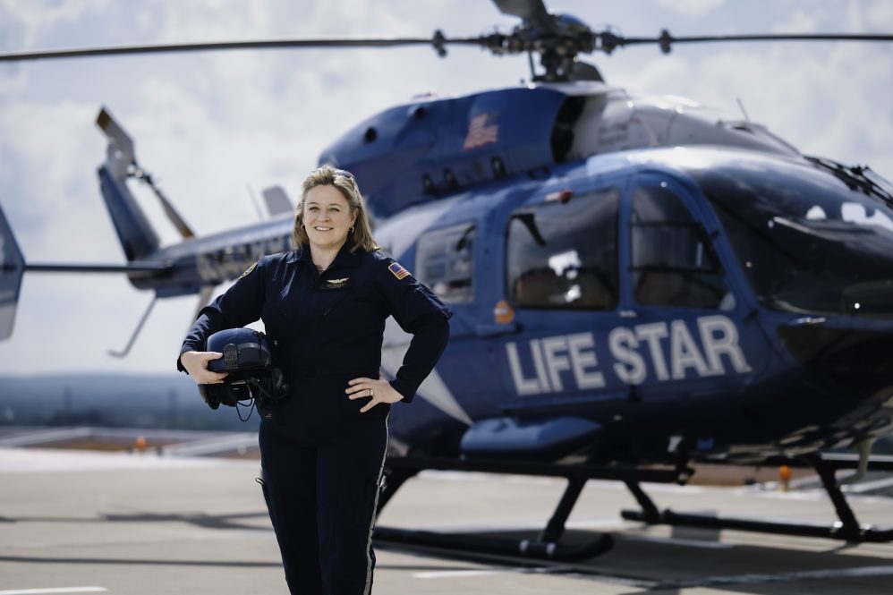 Patricia “Tricia” Margarido, a 2019 graduate of UConn’s Executive MBA program, poses in front of the LIFESTAR helicopter.