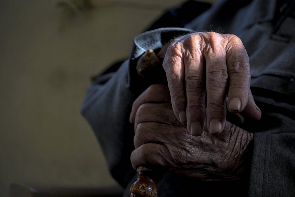 Image of mans hands crossed on a cane.