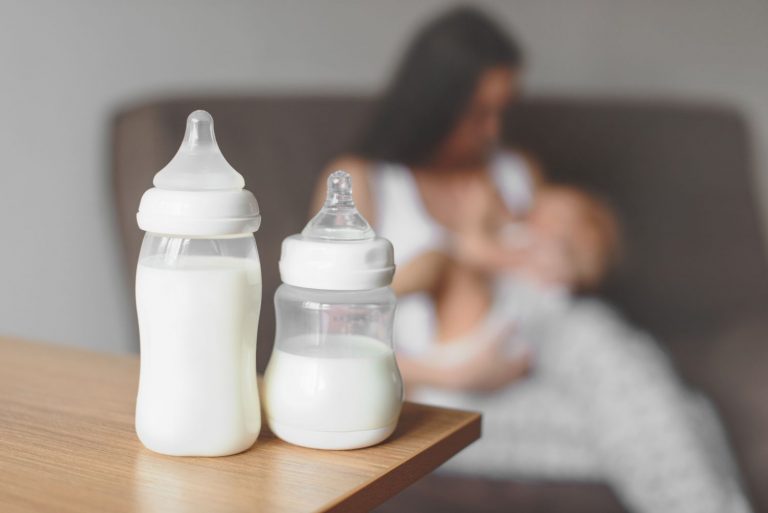 Breastfeeding mother and infant with formula in the foreground