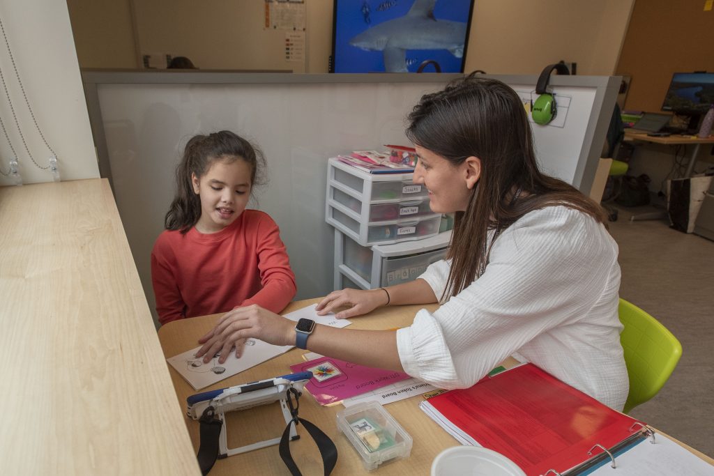 Female Neag School student works with elementary student.