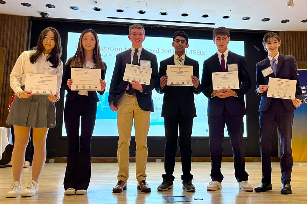 group portrait six students on stage holding award certificates