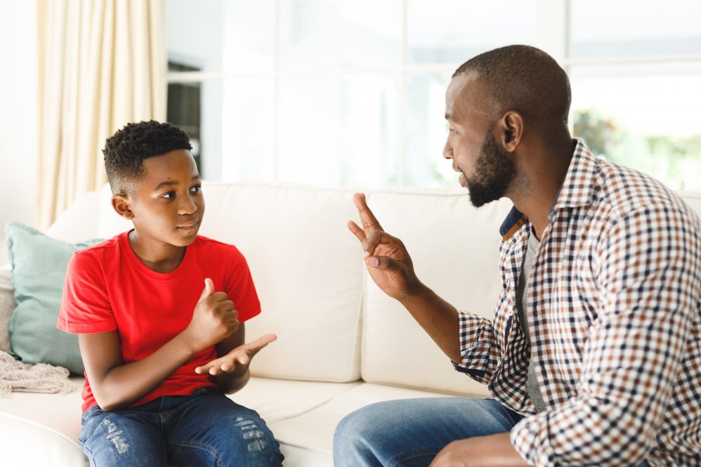 A Black father teaching sign language to his son.