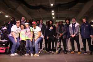 Students on stage at HuskyTHON, including members of the men's basketball team.