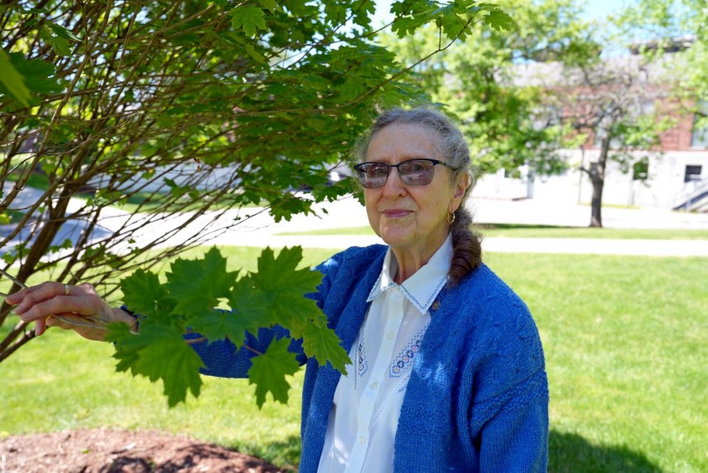 Elderly woman stands near tree