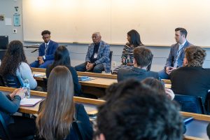 Professional adults participate in panel in front of a classroom of students.