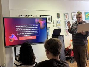 A student reads from a laptop while giving a presentation