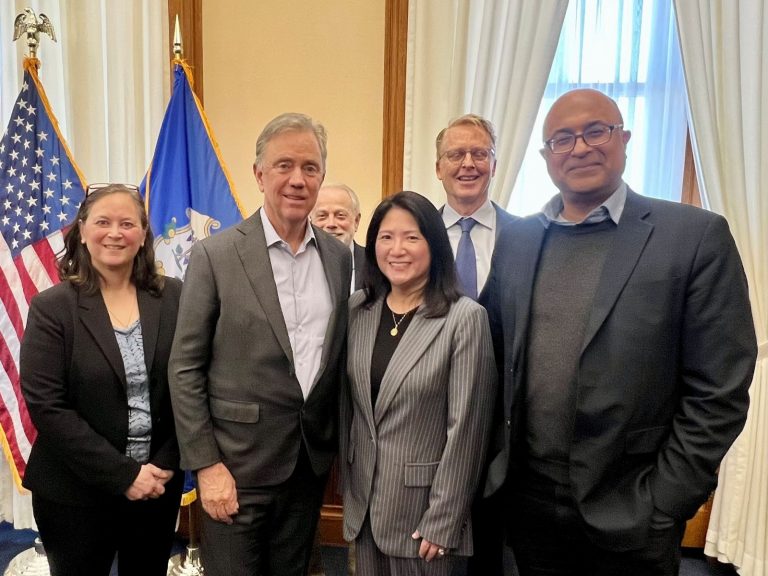 A posed photo of Governor Ned Lamont surrounded by five UConn Law alumni and faculty members who have worked on the bill.