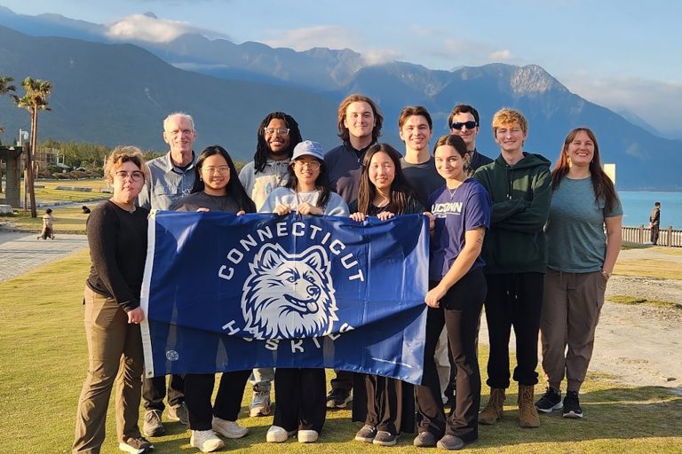 A group of students holding a banner on a study abroad trip.