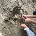 Students hammering at a rock structure. 