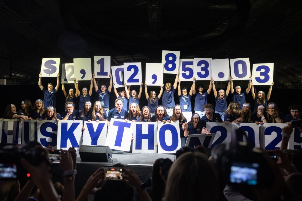 Students holding up cards revealing the number 2,102,853.03