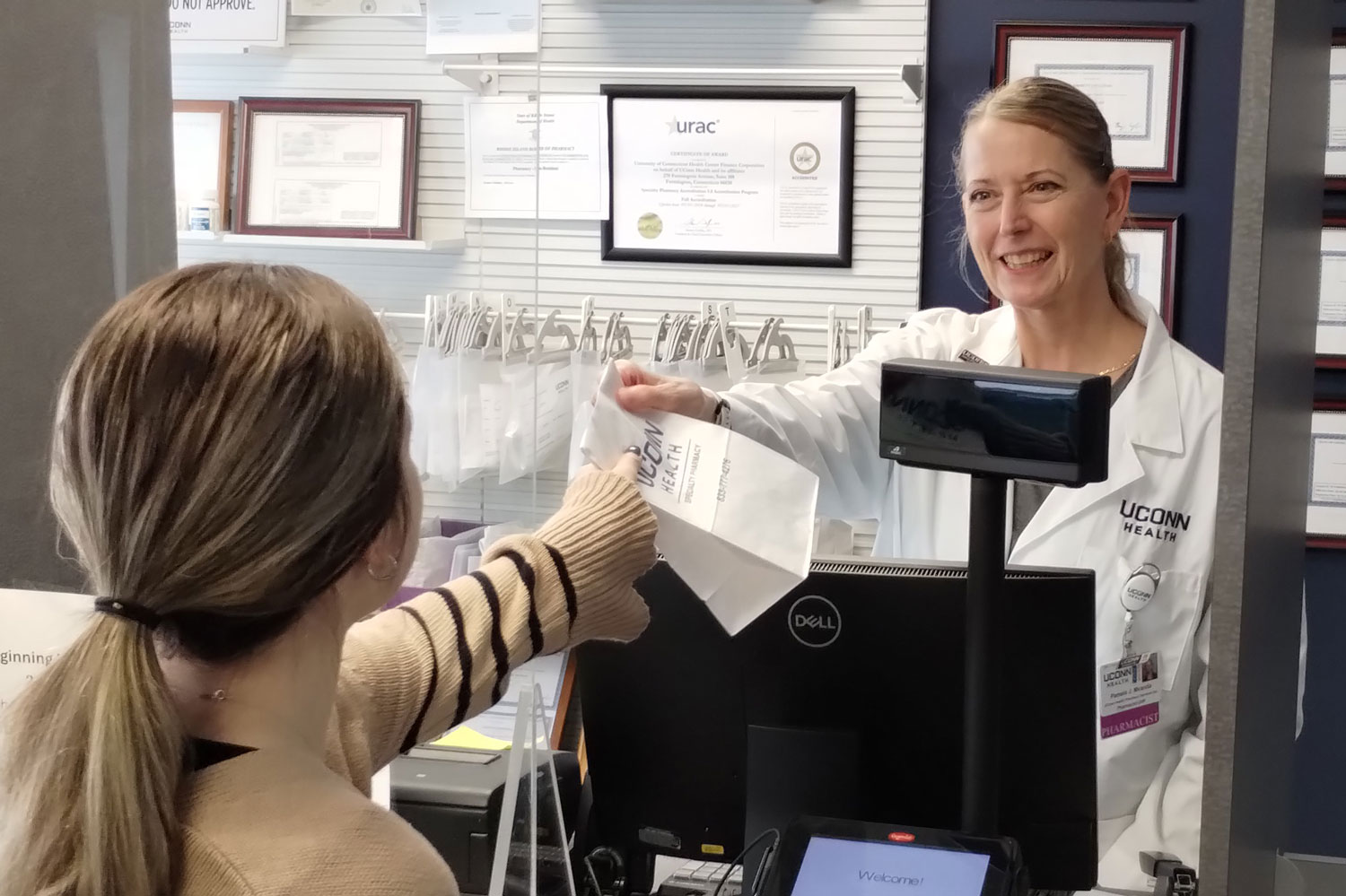 pharmacist hands women a white bag