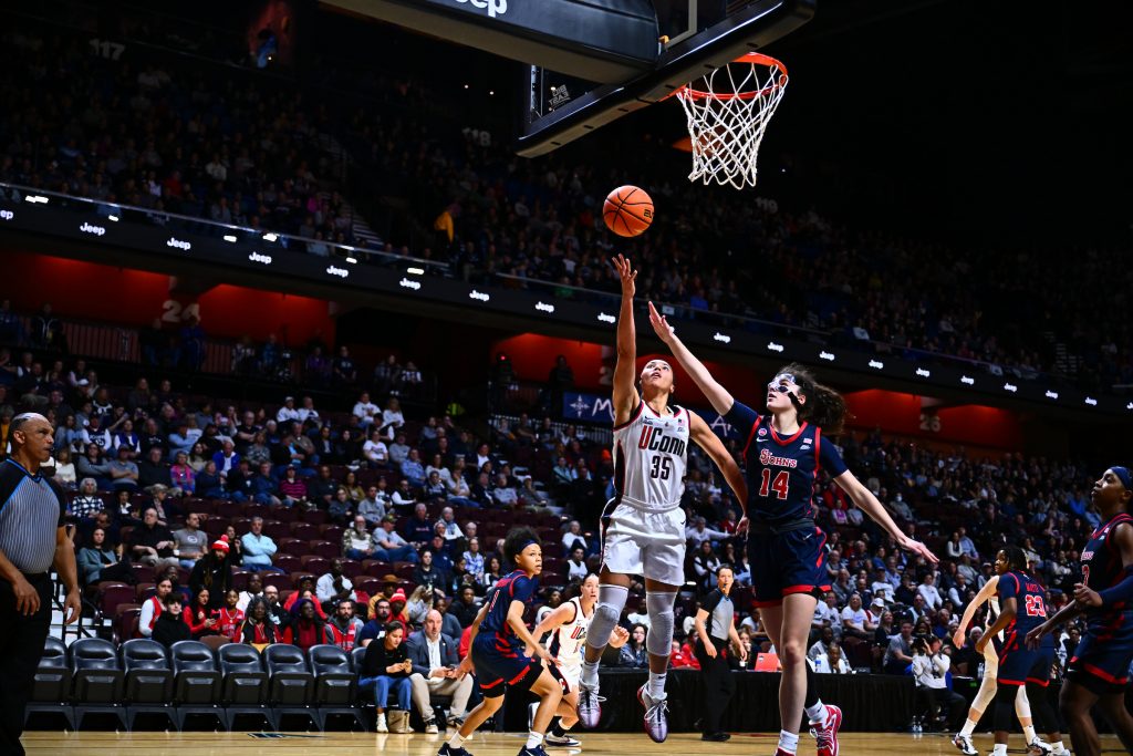 A UConn basketball player goes for a layup in a game against St. John's.