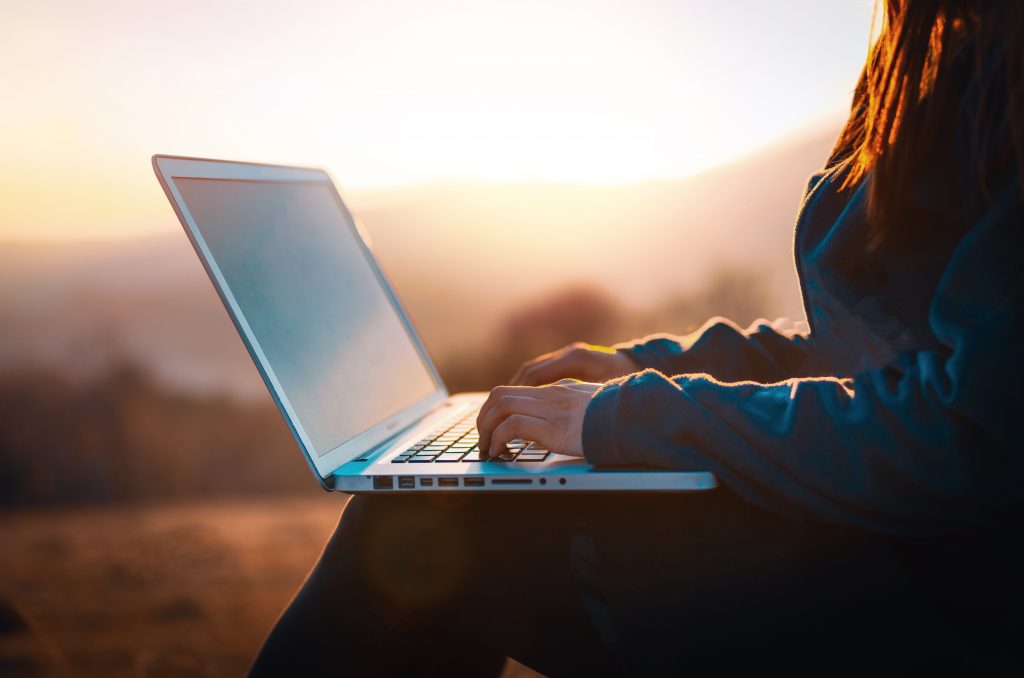 A person using a laptop computer in nature