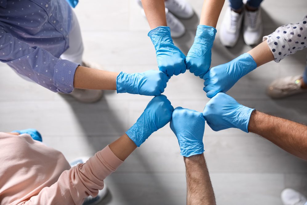 People in blue medical gloves joining fists.