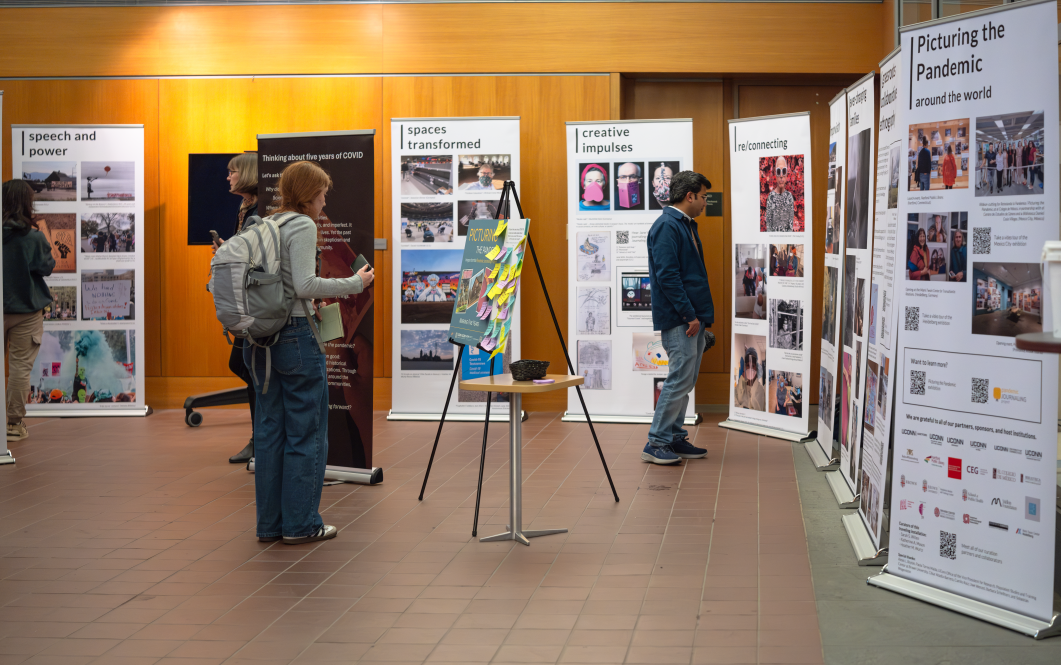 Students look at the tall panels on display at Homer Babbidge Library displaying work from the Pandemic Journaling Project.