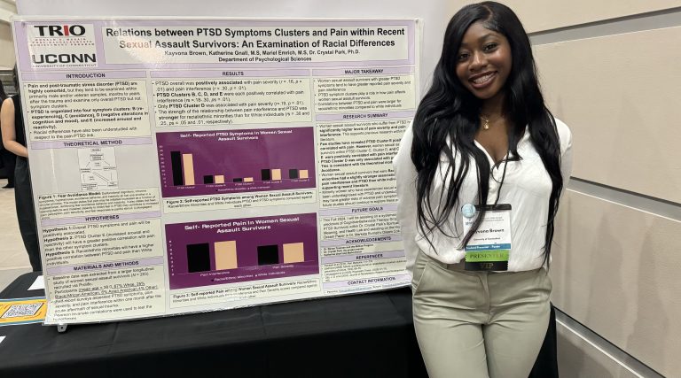 A researcher stands in front of a research poster