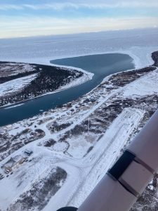 An aerial view of a snow-covered village taken from the window of a small airplane.