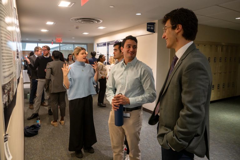 Three young people converse with each other in a crowded room.