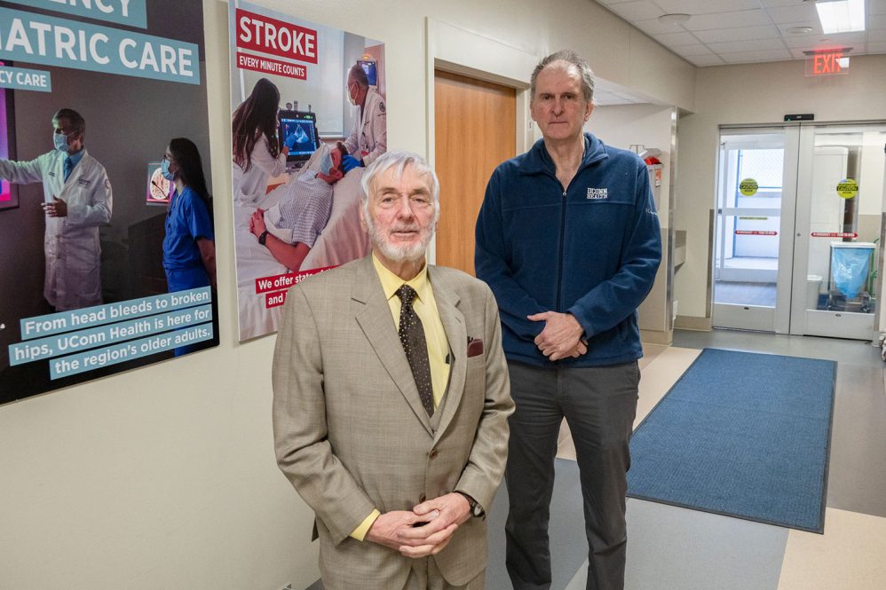 Portrait Dr. Richard Simon and Peter Canning by a stroke poster in the UConn John Dempsey Hospital emergency department