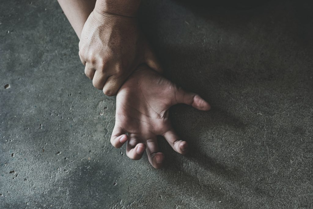 One hand holds another down by the wrist.