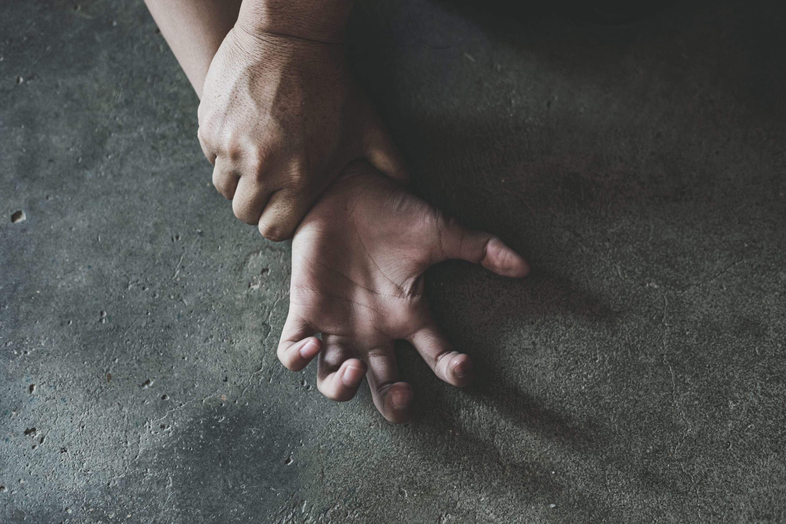 One hand holds another down by the wrist.
