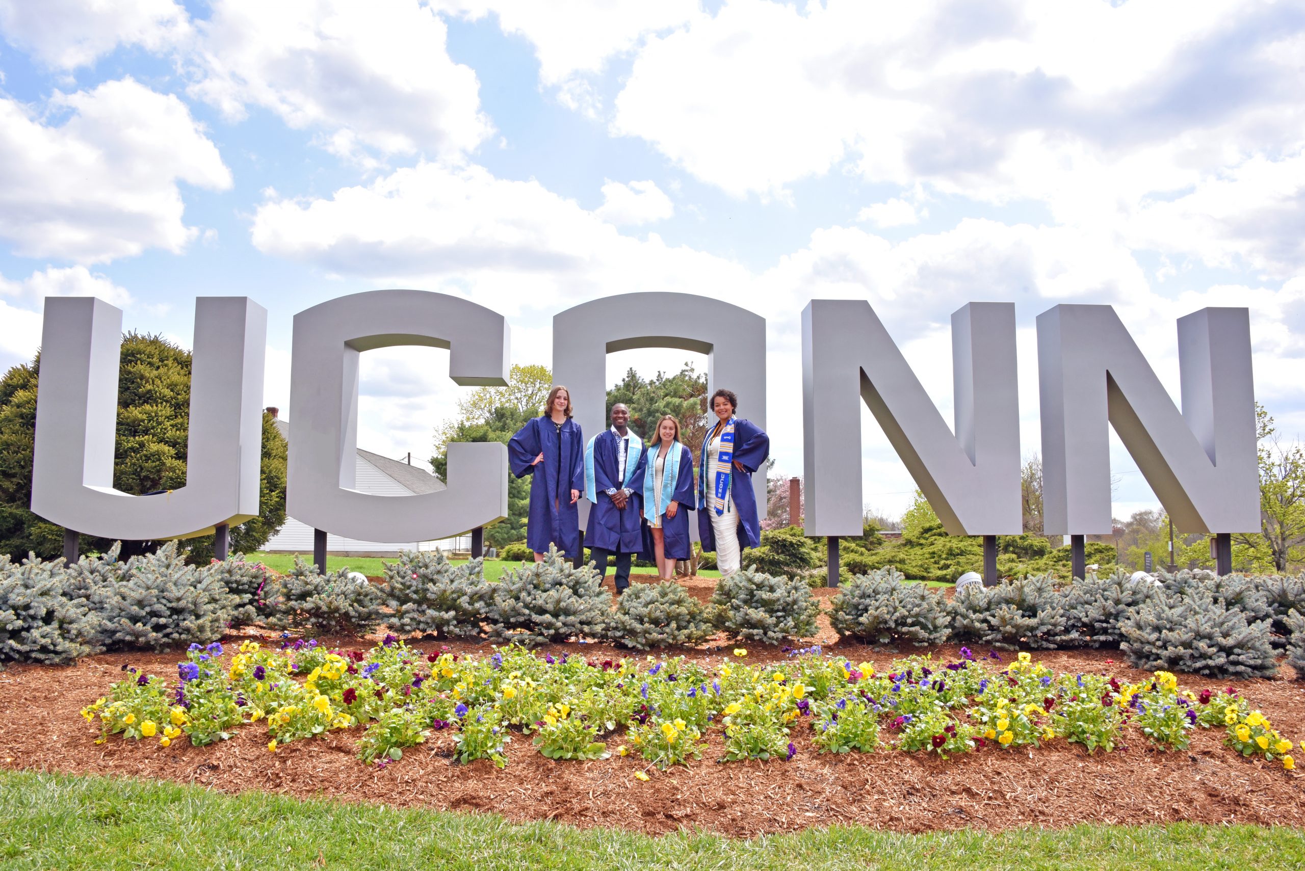 Graduates posing in front of the UConn gateway sign