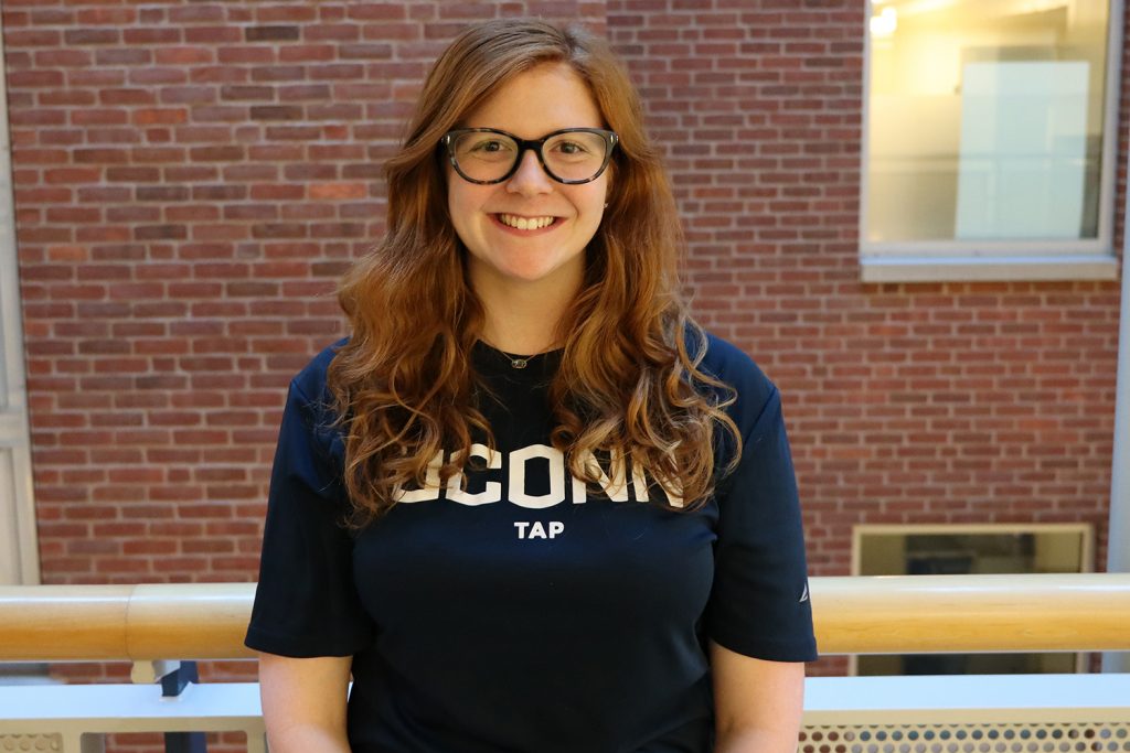 Sara Rosenthal wearing UConn Tap t-shirt stands in the Gentry Building.