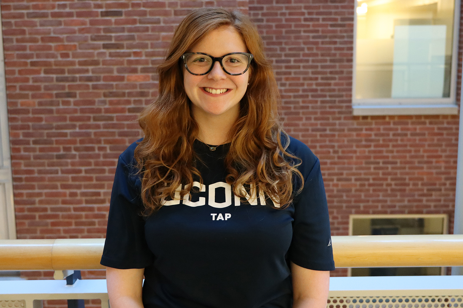 Sara Rosenthal wearing UConn Tap t-shirt stands in the Gentry Building.