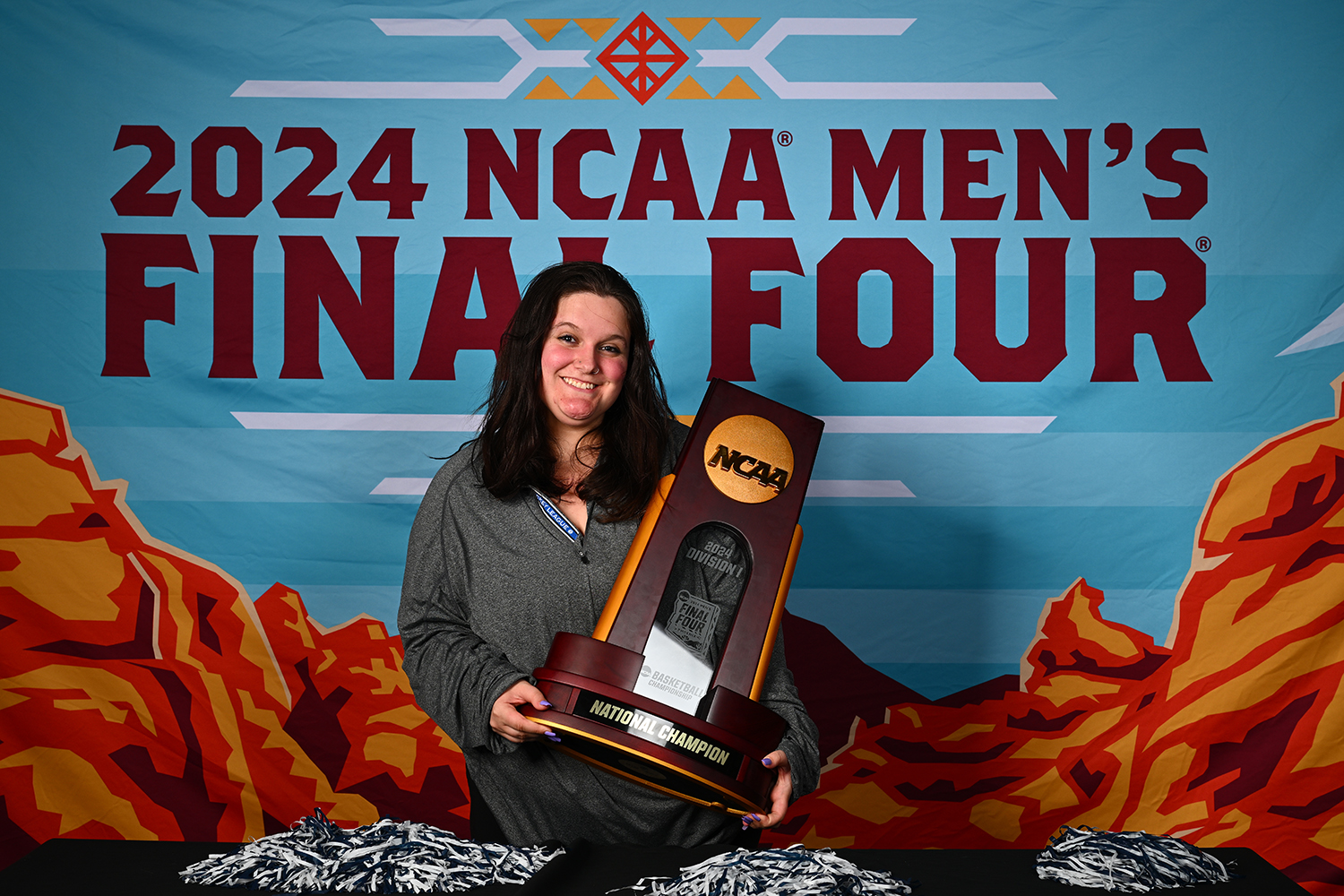Teddi Ferrato holds NCAA trophy in front of NCAA Final Four banner.