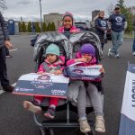 portrait of three young girls, two of them in a double stroller