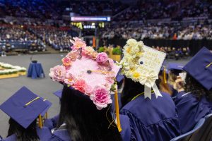 Two elaborately decorated graduation caps are seen from behind.