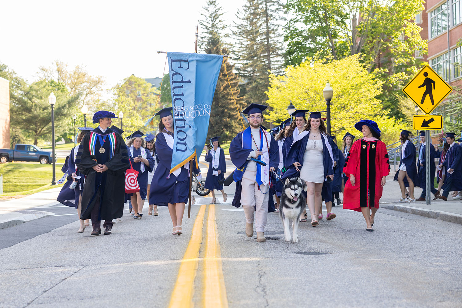 Jonathan VX leads a procession of Neag School of Education graduates outside.