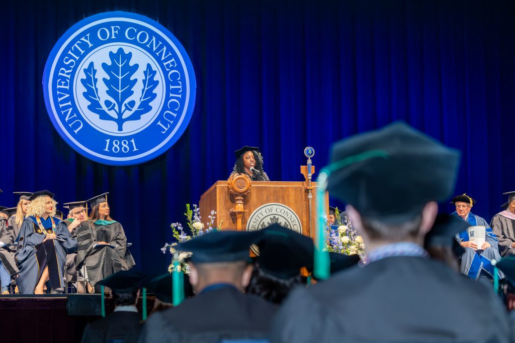Graduate of UConn medical school Dr. Daniella Dennis '25 speaks during UConn Health's Commencement ceremony on May 12, 2025 (Sydney Herdle/UConn Photo).