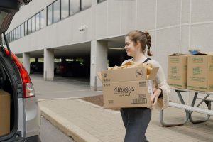 woman carrying a box toward the back of a car